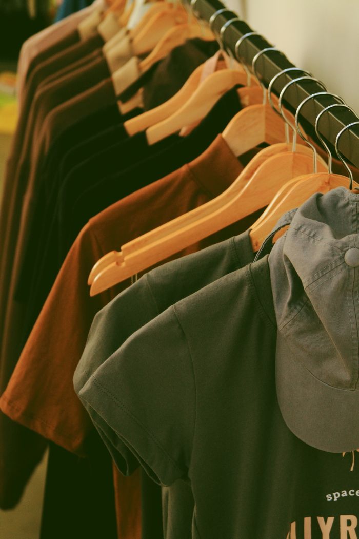 Home Clothing rack with modern streetwear shirts and wooden hangers in a fashion store.