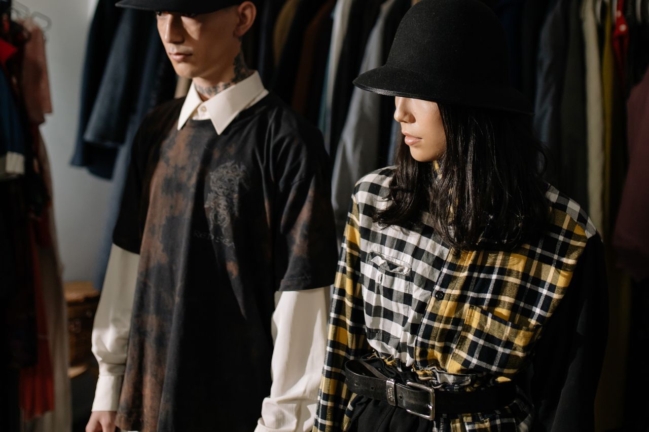 About Fashion-forward man and woman wearing stylish hats and plaid shirts in a clothing store.
