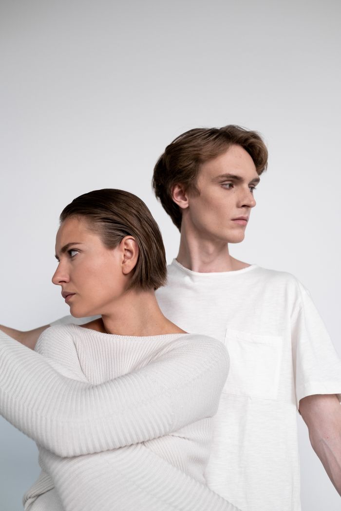 Home A creative studio portrait featuring two people in stylish, minimalist clothing.